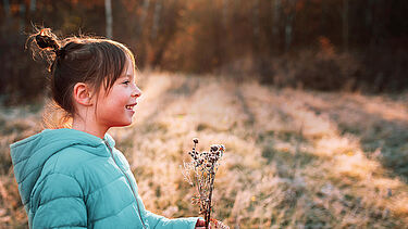 Smiling girl in mint blue jacket in the forest